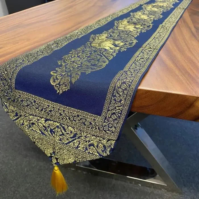 Chemin de Table en Tissu Bleu avec Pompons Dorés. Nappe présentée sur une table en bois