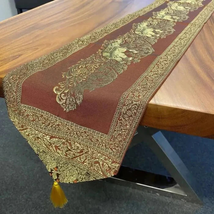 Chemin de Table en Tissu Cuivré avec Pompons Dorés présenté sur une table en bois
