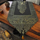 Chemin de Table en Tissu Noir avec Pompons Dorés. Nappe présentée sur une table en bois