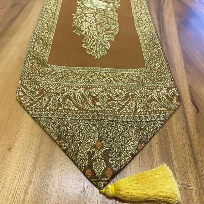 Bout d'un Chemin de Table en Tissu Cuivré avec Pompons Dorés, présenté sur une table en bois