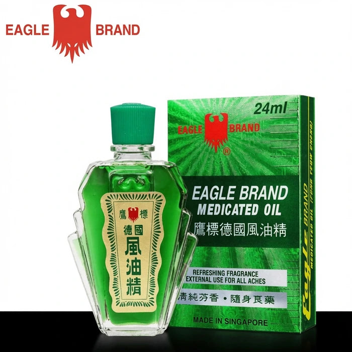 Flacon transparent d’huile médicamenteuse Eagle Brand Medicated Oil, contenant un liquide vert et surmonté d’un bouchon vert. À côté, la boîte verte affiche le logo rouge de l’aigle et des inscriptions en anglais et chinois. Produit fabriqué à Singapour, destiné au soulagement des douleurs et tensions corporelles.