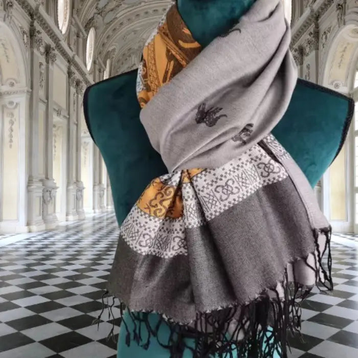 Élégant foulard cachemire et soie gris et doré exposé sur mannequin, dans un palais classique raffiné.