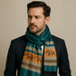 Homme élégant portant un foulard en soie bleu canard orné de motifs éléphants dorés et bruns.