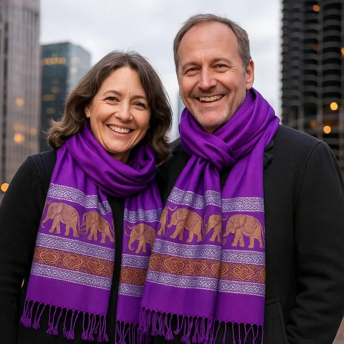 Couple souriant portant des foulards pourpres thaïlandais en soie, ornés d’éléphants dorés traditionnels.