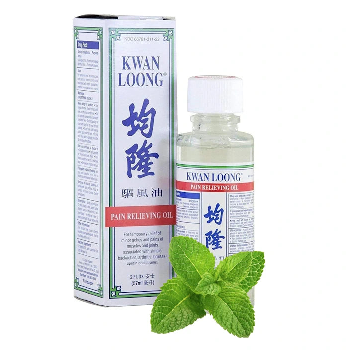 Bouteille et boîte d'huile Kwan Loong, avec des feuilles de menthe pour un effet rafraîchissant.