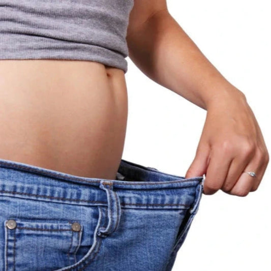 une femme tire son pantalon au niveau de la taille et laisse voir son ventre
