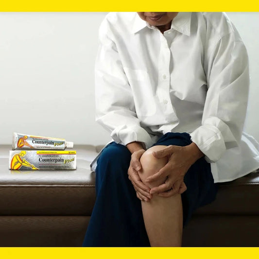 Publicité pour Counterpain. Personne assise tenant son genou. Deux tubes de "Counterpain Plus" sur le canapé. Utilisation pour soulagement de la douleur au genou.
