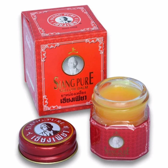 Produit Siang Pure Yellow Balm, avec une boîte rouge ornée de textes en anglais et en thaï, un couvercle rouge et un pot de baume jaune. Utilisé pour soulager les douleurs et les courbatures.