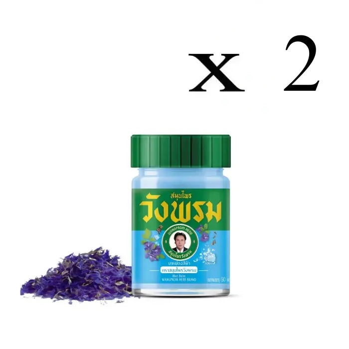 2 Flacons de Baume Wang Prom bleu, avec des fleurs séchées de pois bleu dispersées à côté, mettant en avant le produit et son ingrédient principal.