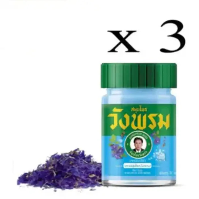 Flacon de Baume Wang Prom bleu, avec des fleurs séchées de pois bleu dispersées à côté, mettant en avant le produit et son ingrédient principal. Mention x 3.